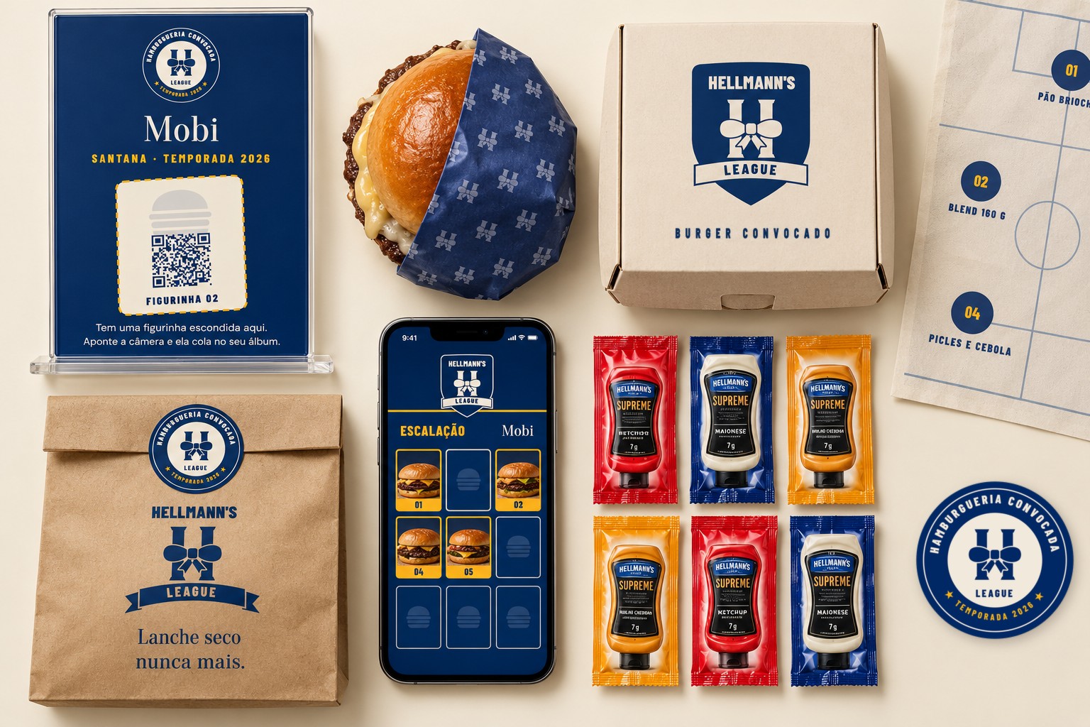 O universo da liga: placa da Mobi, burger no papel azul, caixa, sacola, papel de bandeja, selo, o álbum no celular e os sachês Supreme